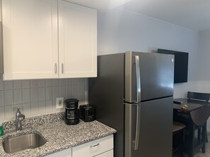 A kitchen with white cabinets, a stainless steel refrigerator, a coffee maker, and a toaster.