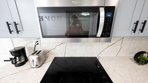 Una cocina moderna equipada con microondas, cafetera, tostadora y una cocina por inducción negra.