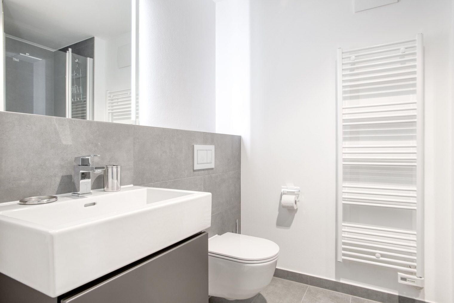 A modern bathroom with a white sink, mirror, and toilet.