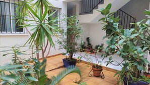Tilava sisätila, jossa on useita ruukkukasveja, laatoitettu lattia ja portaikko, joka johtaa ylemmälle tasolle.