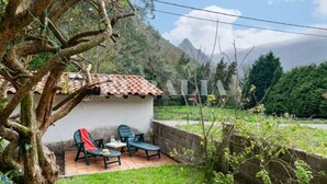 A small outdoor seating area with a table and chairs, a tree, and a building with a tiled roof. - Casina de Cuevas - country house in Cuevas del Agua (Ribadesella) (Nocedo (Cuevas Del Agua))