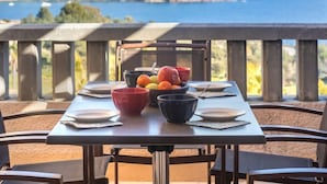 A table set for dining with a view of the sea and a distant shoreline. - Le Village (E1 309) by Interhome (Agay Village Cap Esterel)