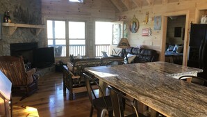 A rustic kitchen with a large granite countertop, wooden beams, stone walls, and a fireplace. - Fantastic Mountain Views Plus Hot Tub and Fire Pit!! (Blue Ridge)