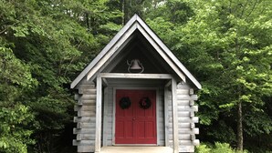 A wooden cabin with a red door, a bell above the door, and a wreath on either side. - Fantastic Mountain Views Plus Hot Tub and Fire Pit!! (Blue Ridge)