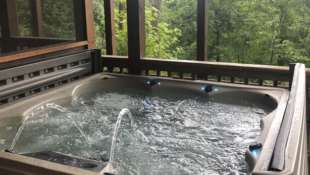 A hot tub with water jets, surrounded by wooden beams and a view of a forest. - Fantastic Mountain Views Plus Hot Tub and Fire Pit!! (Blue Ridge)