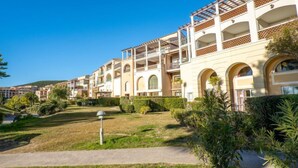 Ein mehrstöckiges Hotel mit Balkonen, einem gepflegten Garten und blauem Himmel.