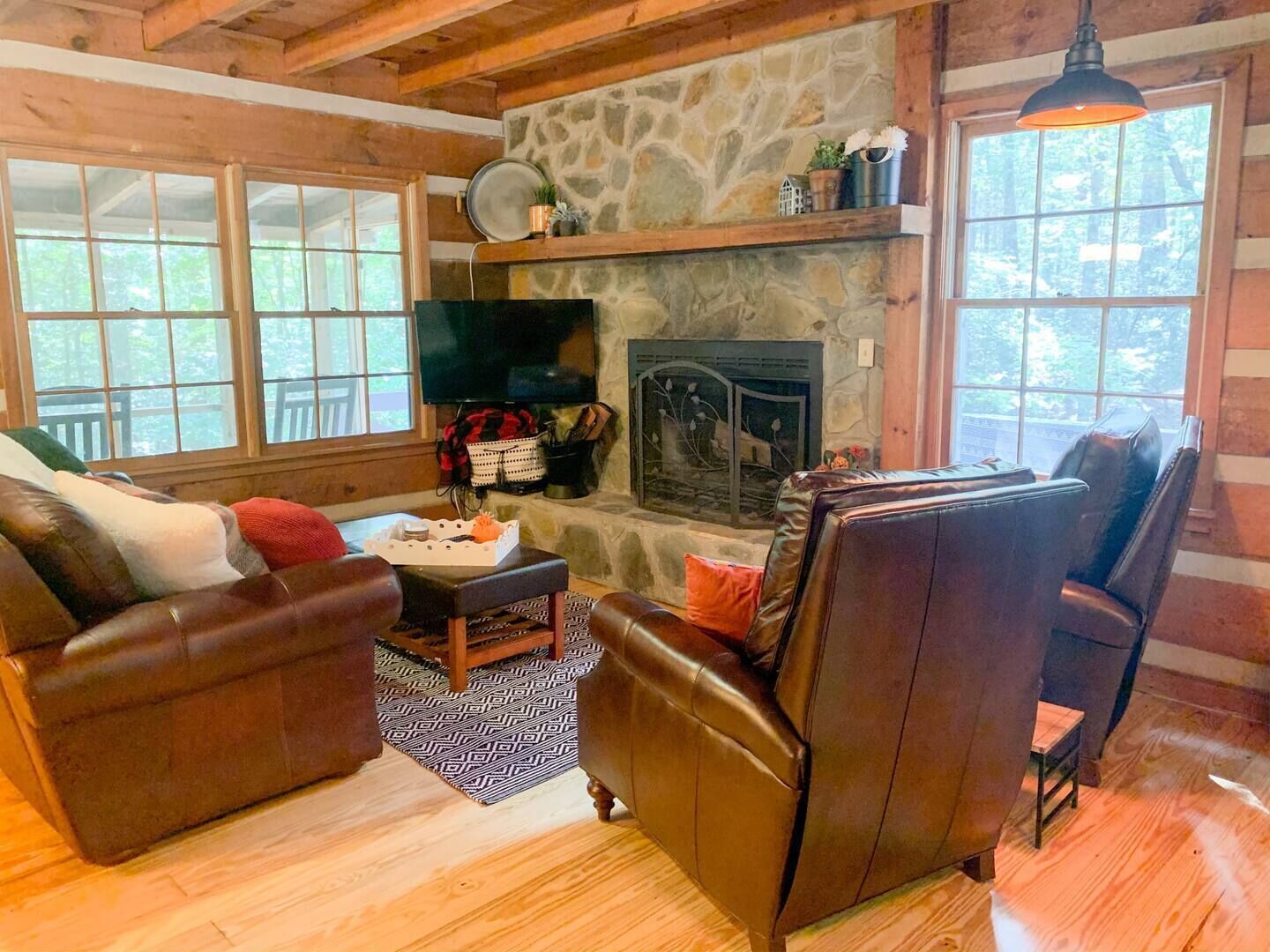 A cozy living room with a stone fireplace, leather sofas, and a television.