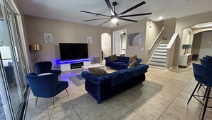 Ein modernes Wohnzimmer mit Flachbildfernseher, blauen Sofas und Deckenventilator.