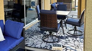 Eine sonnendurchflutete Terrasse mit Deckenventilator, einem Esstisch mit Stühlen und einem blauen Sofa.