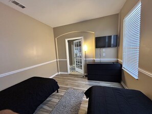Une chambre d’hôtel avec deux lits, une télévision, un bureau et une porte donnant sur un balcon.