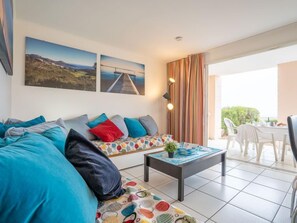 A modern living room with a sofa, colorful cushions, a coffee table, and two paintings on the wall.
