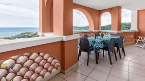Un balcón con una mesa lista para cuatro personas, con vistas a un paisaje pintoresco.
