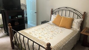A neatly arranged bedroom with a bed, a television on a stand, a door, and a small table. - Oceanfront condo in Pinnicle Port on the west end of Panama City Beach. (Panama City)