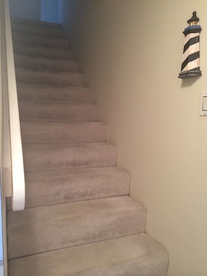 Staircase with carpeted steps and a wall-mounted light fixture.