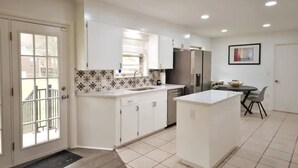 A modern kitchen with white cabinets, a tiled backsplash, and stainless steel appliances. - Golden Racehorse MCM 3BR Slps 6 - 7 Min to Oaklawn (Hot Springs)