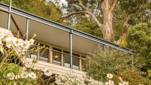 A modern house with a balcony overlooking a garden with white flowers. - Hanging Garden On Mernda- Mountain view retreat  (Olinda)