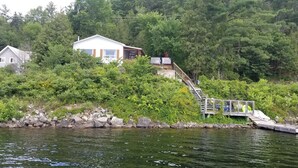 Järvenrantamökki, jossa on puinen laituri ja pieni vene.