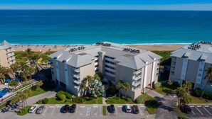 A beachfront hotel with multiple floors, a parking lot, and a beach view. - The Sea Turtle at Spoonbill Resort Villa (Stuart)