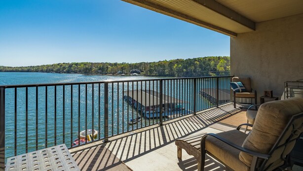 Un balcón con vistas a un lago, un muelle con barcos y una terraza de madera.