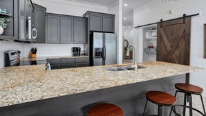 Una cocina moderna con encimeras de granito, armarios oscuros y una isla central con taburetes de bar.