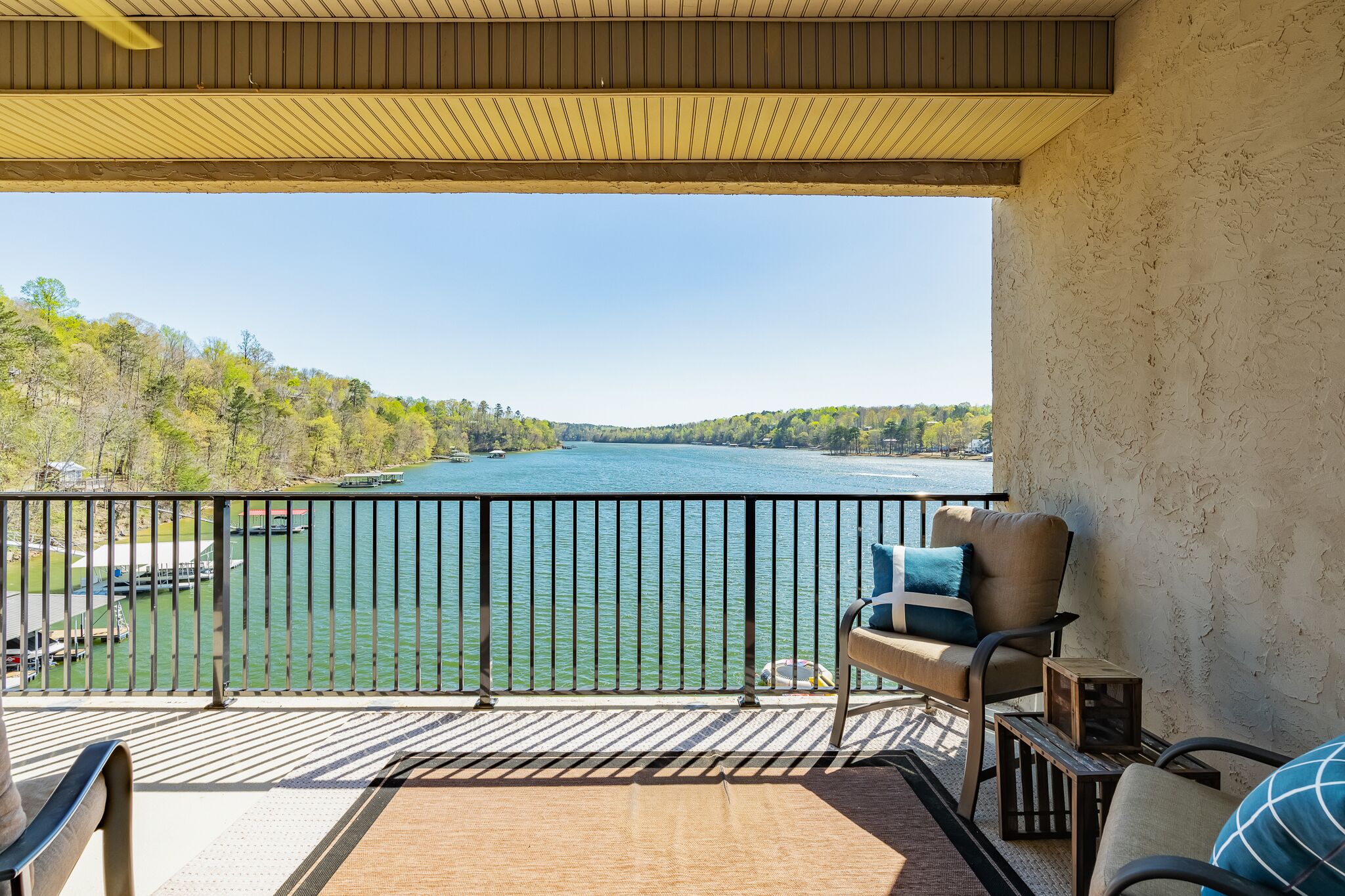 Un balcon avec vue sur un lac, un plafond en bois et un coin salon avec des coussins.