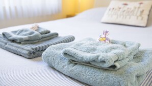Una cama bien tendida con toallas dobladas y un cartel de habitación de hotel a la vista.