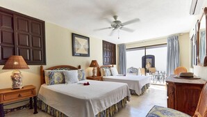 A hotel room with two beds, a ceiling fan, a dining area with a table and chairs, and large windows with curtains. - Casa Mismos w/pool |Walk to Medano Beach + Marina (Cabo San Lucas)