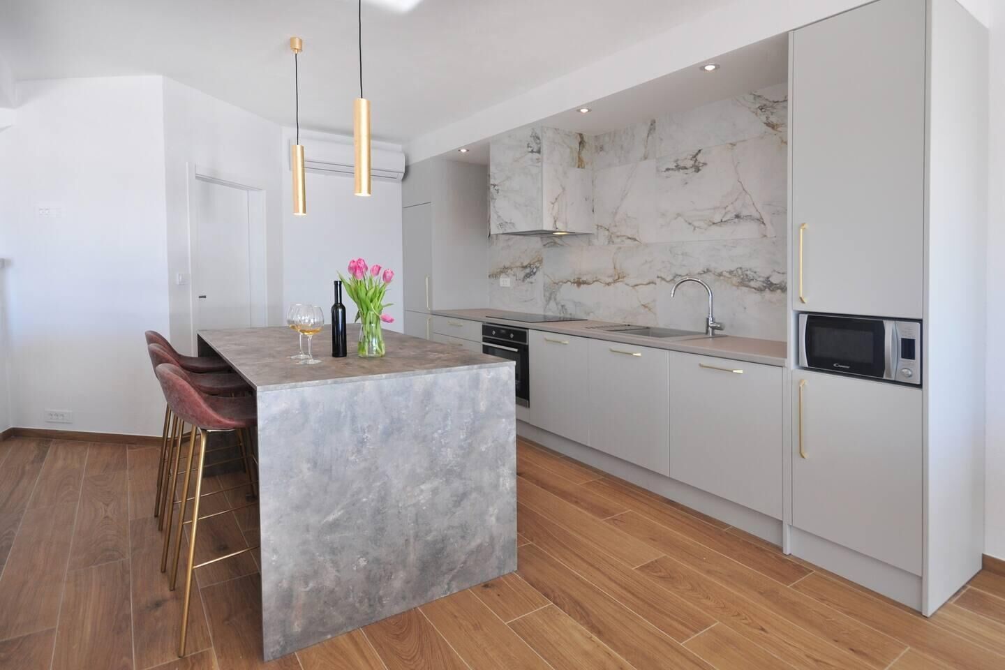 A modern kitchen with a marble backsplash, a central island, and pendant lighting.