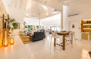 Relax in a spacious living area with a high ceiling, comfortable seating, and a dining table for meals or gatherings.