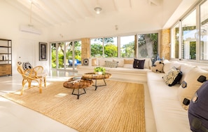 Relax in this serene space with a large sofa, wicker chair, and bookshelf.