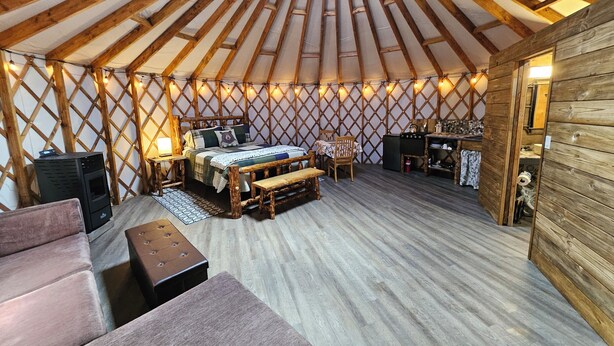 A yurt interior with a bed, seating area, and a small kitchenette.