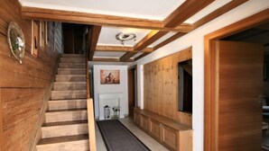 A wooden staircase leading to a hallway with a fireplace, a bench, and a door. - Lamplberg by Interhome (Hippach)