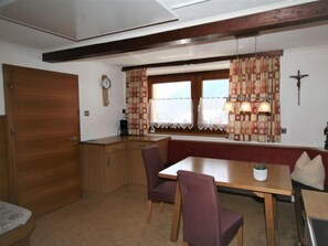 A compact kitchen with wooden cabinets, a built-in bench, and a dining table with chairs.