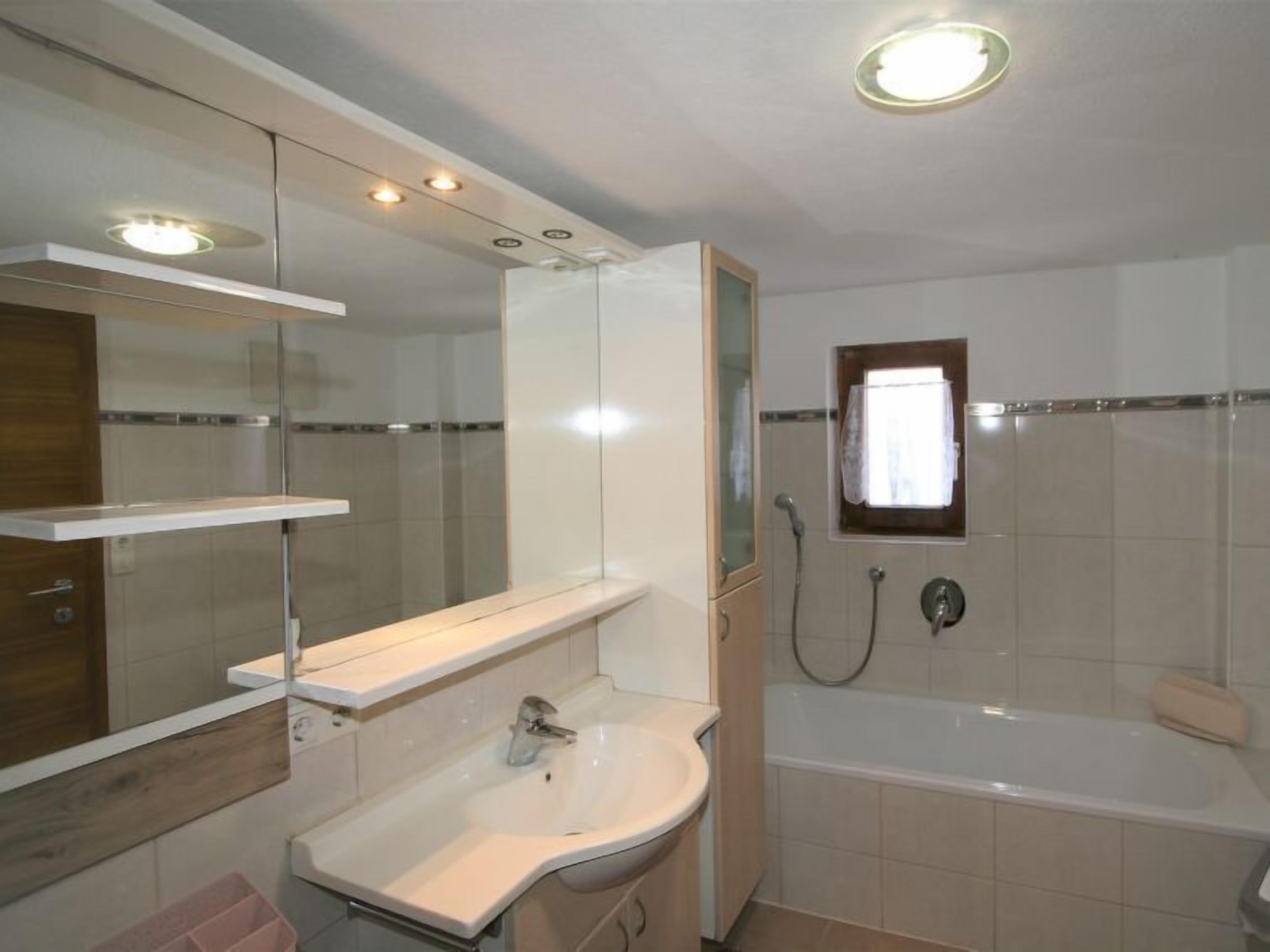 Une salle de bain moderne avec un lavabo blanc, un miroir, une douche et une baignoire.