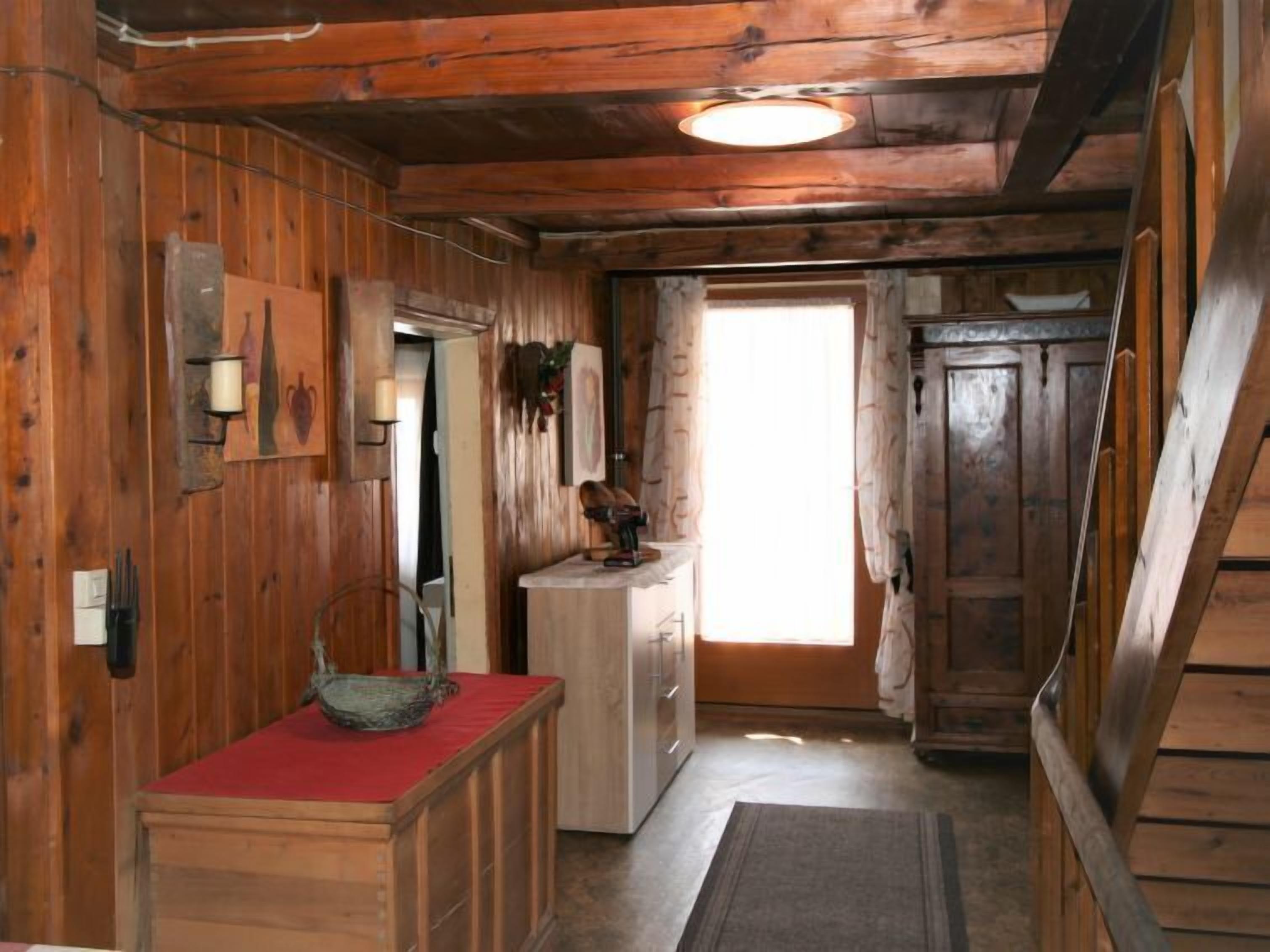 Un intérieur en bois avec un banc, une porte et un luminaire.