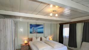 A modern bedroom with a wooden bed, bedside lamps, a painting, and a view of the outdoors. - Lamplberg by Interhome (Hippach)