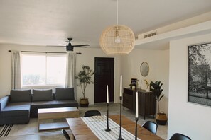 Una sala de estar moderna con sofá, mesa de comedor y ventilador de techo.