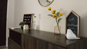 A wooden counter with decorative items including a sign, a vase with flowers, and a bird figurine. - The Desert Sunset: 4 BDR, 5 Beds, Fast Wifi, Large TV, Large private pool, (Mesa)