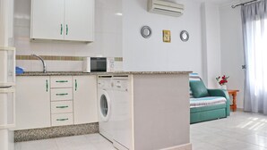 A modern kitchen with white cabinets, a microwave, a washing machine, and a small island. - First floor Apartment Santa Teresa (Conil de la Frontera)