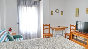 A room with a bed, a desk, a chair, a television, and a window with curtains. - First floor Apartment Santa Teresa (Conil de la Frontera)