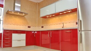 Eine moderne Küche mit roten Schränken, Edelstahlgeräten und einer gefliesten Spritzschutzwand.