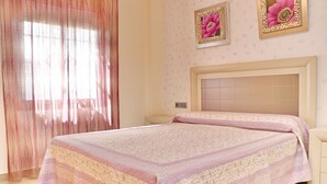 Ein Schlafzimmer mit einem Bett, Vorhängen und zwei gerahmten Bildern an der Wand.