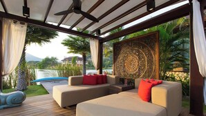 Un espacio al aire libre con dos sofás, un muro decorativo y vista a un cuerpo de agua.