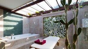 Un cuarto de spa con una bañera, una camilla de masajes y una planta de cactus.