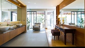 Un baño moderno con un espejo grande, un lavamanos y un banco.