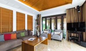 Una sala de estar moderna con un sofá, sillones, una mesa de centro, un televisor y persianas de madera.