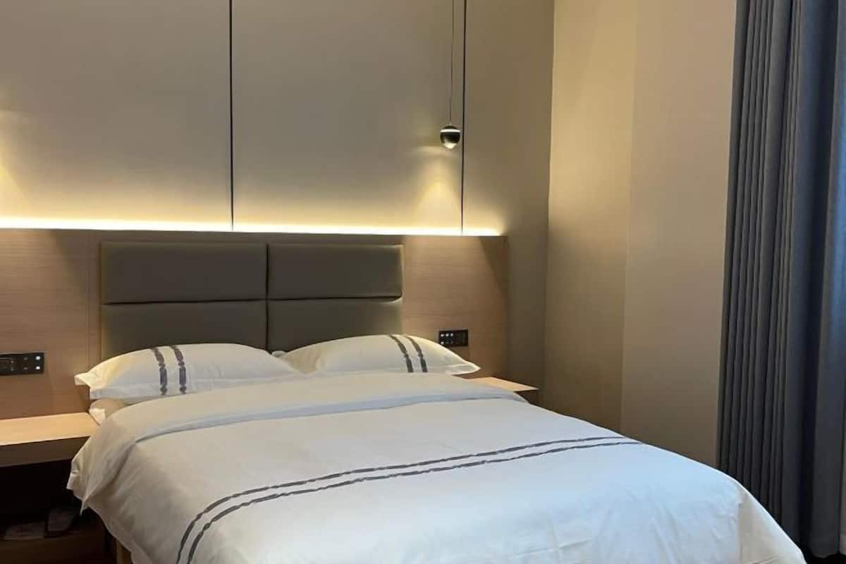 Habitación de hotel con cama, mesitas de noche y cabecera con iluminación integrada.