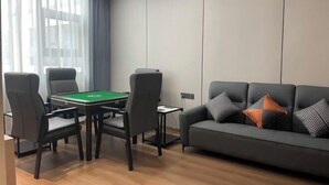 Een moderne woonkamer met een pooltafel, een bank met geborduurde kussens en een groot raam met dunne gordijnen.