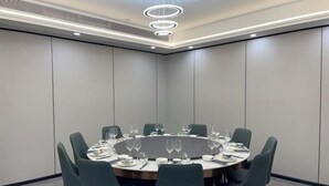 Een vergaderruimte met een ronde tafel, stoelen en een modern plafondontwerp.