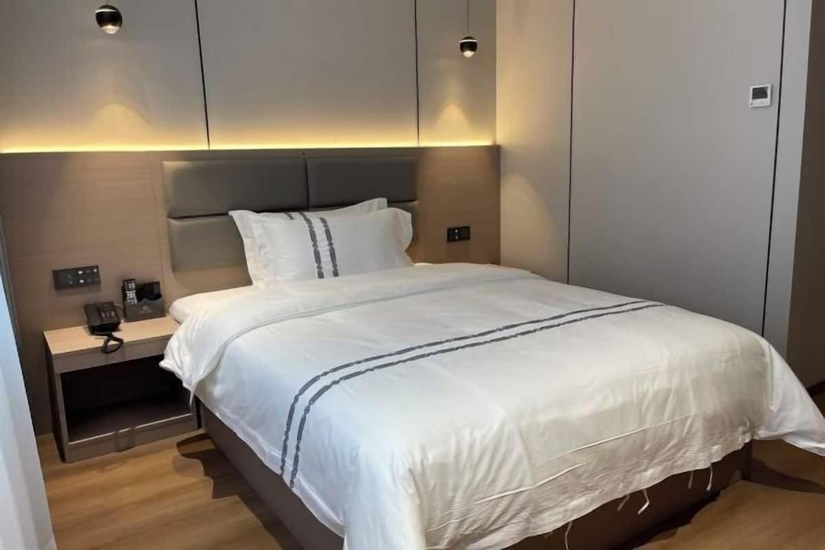 Una habitación de hotel moderna con una cama grande, mesitas de noche e iluminación empotrada.